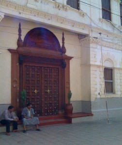Two Muslim men seated in front of a Zanzibar door during Ramadan.