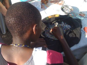 A girl living at Pippi House makes beaded necklaces to sell and raise money.